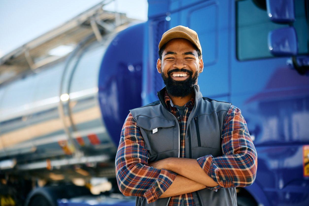 Smiling commercial truck driver standing in front of his rig